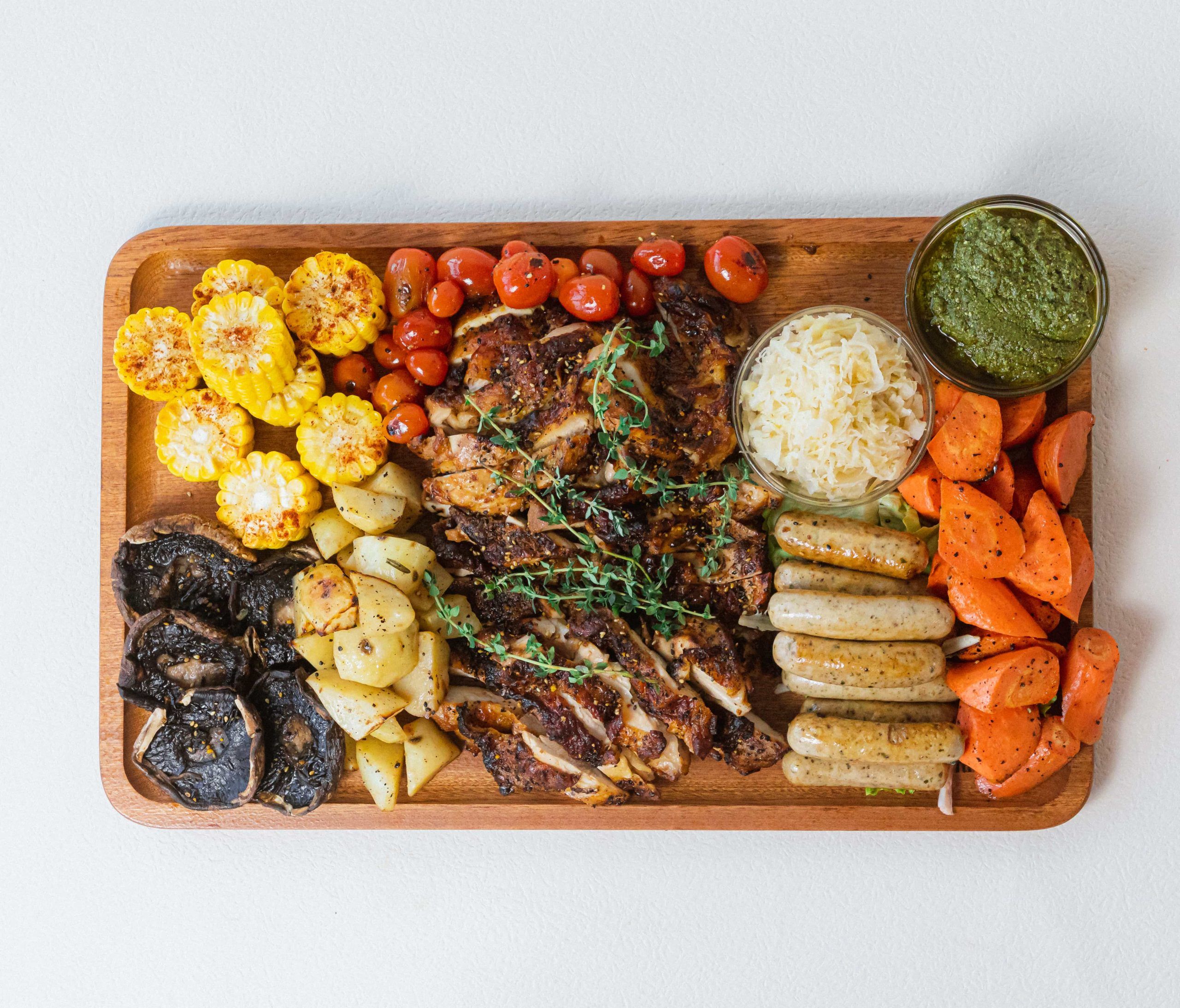Rustic grilled chicken thigh and sausage platter for sharing, ideal for parties in Singapore